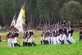 A group of soldiers-reenactors march with a flag.