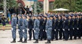 Group of soldiers in uniform, standing with a senior officer behind them in an outdoor area