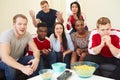 Group Of Sports Fans Watching Game On TV At Home