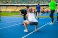 Group of sportsmen do the exersises on the stadium. squat and stretch. Royalty Free Stock Photo