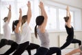 Group of sporty people practicing yoga, doing Warrior 1 pose Royalty Free Stock Photo