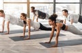 Group of sporty people practicing yoga together, standing in plank phalankasana pose Royalty Free Stock Photo