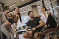 Group of sporty people in sportswear taking selfie photo with mobile phone at gym