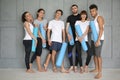 Group of sporty people with yoga mats near grey wall