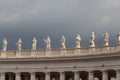 Group of statues of Peter`s Square Colonnade with rainy clouds on background, Vatican city state, Italy