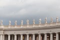 Group of statues of Peter`s Square Colonnade with rainy clouds on background, Vatican city state, Italy