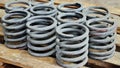 Group of steel springs of shock absorbers on wooden palete. Spare parts of heavy industrial machinery