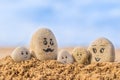 Group of stones with drawn faces in the sand