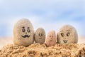 Group of stones with drawn faces in the sand