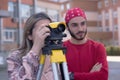 Group of students of architecture doing practice lessons as Surveyor Engineering. SurveyorÃ¢â¬â¢s telescope at construction site for