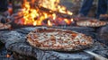 A group of students gathered around a large open fire learning how to make traditional woodfired pizza in an outdoor Royalty Free Stock Photo