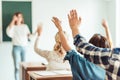 group of students raising hands in class