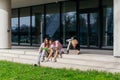 Group of students studying and using laptops outside a modern university building on a sunny day Royalty Free Stock Photo