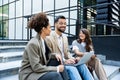 Group of successful young business people, leaders in marketing and motivation, stand in front of office building and consult Royalty Free Stock Photo