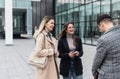 Group of successful young business people, leaders in marketing and motivation, stand in front of office building and consult Royalty Free Stock Photo