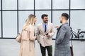 Group of successful young business people, leaders in marketing and motivation, stand in front of office building and consult Royalty Free Stock Photo