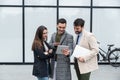 Group of successful young business people, leaders in marketing and motivation, stand in front of office building and consult Royalty Free Stock Photo