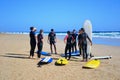 A group of surfers with their boards on the sunny beach of Fuerteventura.