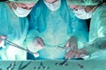 Group of surgeons in masks performing operation. Scene of operation room colored in green. Medicine, surgery and