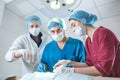 Group of surgeons at work operating in surgical theatre. Resuscitation medicine team wearing protective masks holding Royalty Free Stock Photo