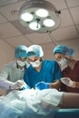 Group of surgeons at work operating in surgical theatre. Resuscitation medicine team wearing protective masks holding Royalty Free Stock Photo