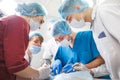 Group of surgeons at work operating in surgical theatre. Resuscitation medicine team wearing protective masks holding Royalty Free Stock Photo