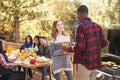 Group at a table behind two friends talking at a barbecue