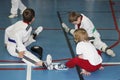 A group of taekwondo sitting on the floor for a rest.