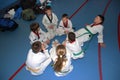 A group of taekwondo sitting on the floor for a rest.