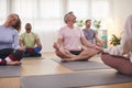 Group With Teacher Sitting On Exercise Mats Stretching In Yoga Class Inside Community Center Royalty Free Stock Photo