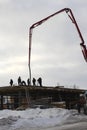 Group team of builders working on the construction of the building in the winter pour concrete with special construction equipment