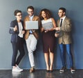 Group or team of business people working and browsing with wireless technology in studio against a grey background Royalty Free Stock Photo