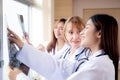 Group of team doctors examining x-ray film about skull and skeleton of patient for checking disease while discussion.