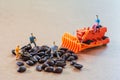 Group of teamwork miniature people, small model human figure and orange tractor check coffee beans for made the best coffee