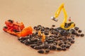 Group of teamwork miniature people, small model human figure and orange tractor and yellow excavator to check coffee beans for