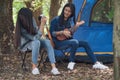 Group of teenage asian girls camping and resting at forest playing ukulele and take a photo happy together. Royalty Free Stock Photo