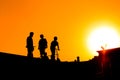 Group of teenage boy silhouettes with scooters standing against sunset sky