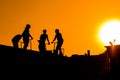 Group of teenage boy silhouettes with scooters standing against sunset sky