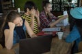 Group of teenage friends working and meeting in team with reports and laptop on wooden table