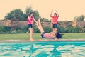 Group of 3 teenage girlfriends having fun in swimming pool. Play throwing each other in the pool Royalty Free Stock Photo