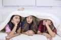 Group of teenage girls confides under blanket