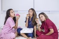 Group of teenage girls eating donuts in bed