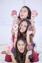 Group of teenage girls holding donuts in bed