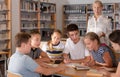 Group of schoolers discussing with adult teacher Royalty Free Stock Photo