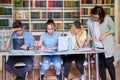 Group of teenage students studying in library class with female teacher mentor Royalty Free Stock Photo