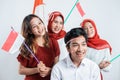 Group of teenage wearing red and white attributes carrying pompom and Indonesian small flags