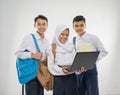 group of teenage wearing school uniforms using a laptop computer together while carrying a backpack and a book