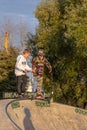 Group of teenager boys skateboarding and scooter riding in the park.