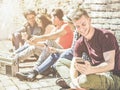 Group of teenagers friends having fun using mobile phones outdoor in old city town - Young people in social moment listening music Royalty Free Stock Photo