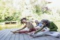 Group of teenages is engaged in fitness on pier by the lake or river. Young and positive girls go in for sports